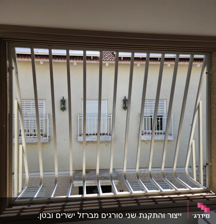 סורגים מתכתיים על חלון עם מסגרת עץ